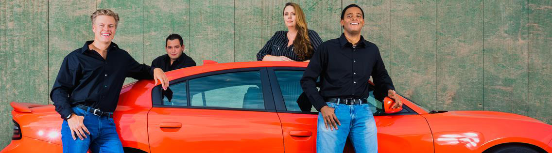 Red sports car with staff at M & S Auto Sales standing around the car smiling.