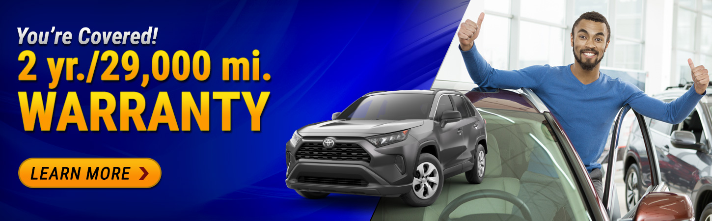 Man standing next to car in dealership. Text reads you're covered. 2 year 29,000 mile warranty available. Learn more.